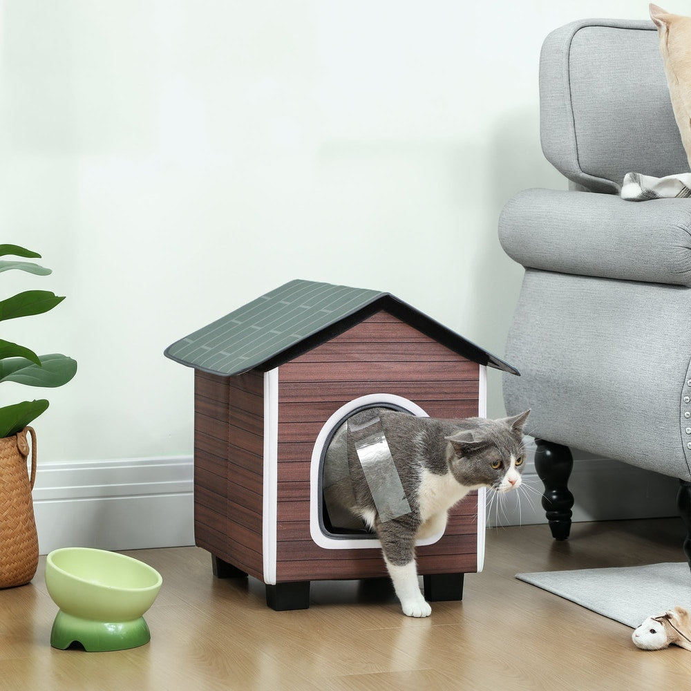 The outdoor cat shelter shown indoors with a grey cat entering through the arched doorway