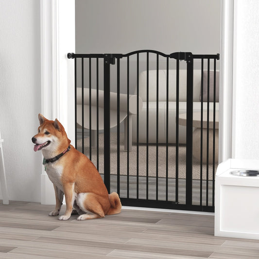 The black metal dog gate is installed in a doorway with a dog sitting beside it
