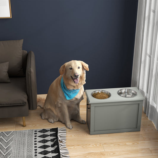 A large dog sits next to the grey dog bowls with storage unit in a living room setting