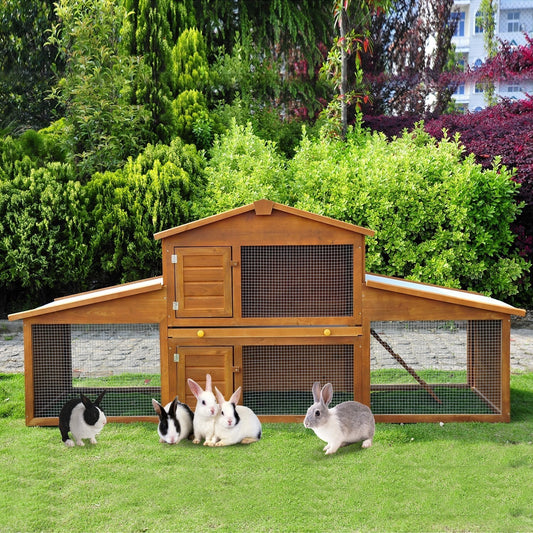A two-tier wooden guinea pig hutch with rabbits and guinea pigs in the garden