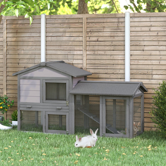 The guinea pigs hutch placed on a lawn in a garden with two white rabbits in front