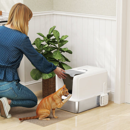 The cat litter box placed on a floor in a room with a woman and a cat nearby