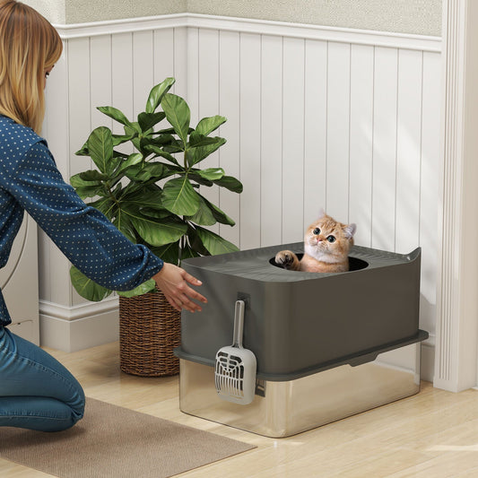 A cute cat peers out from the top entrance of the enclosed litter box while a person places it in a room