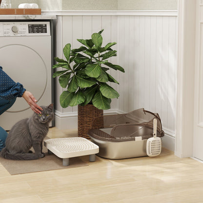 The stainless steel litter box placed on a floor next to a cat and a green houseplant