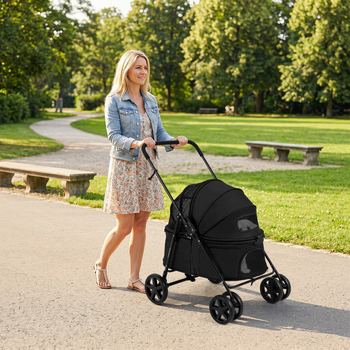 The dog stroller with the canopy closed being pushed by a woman along a path