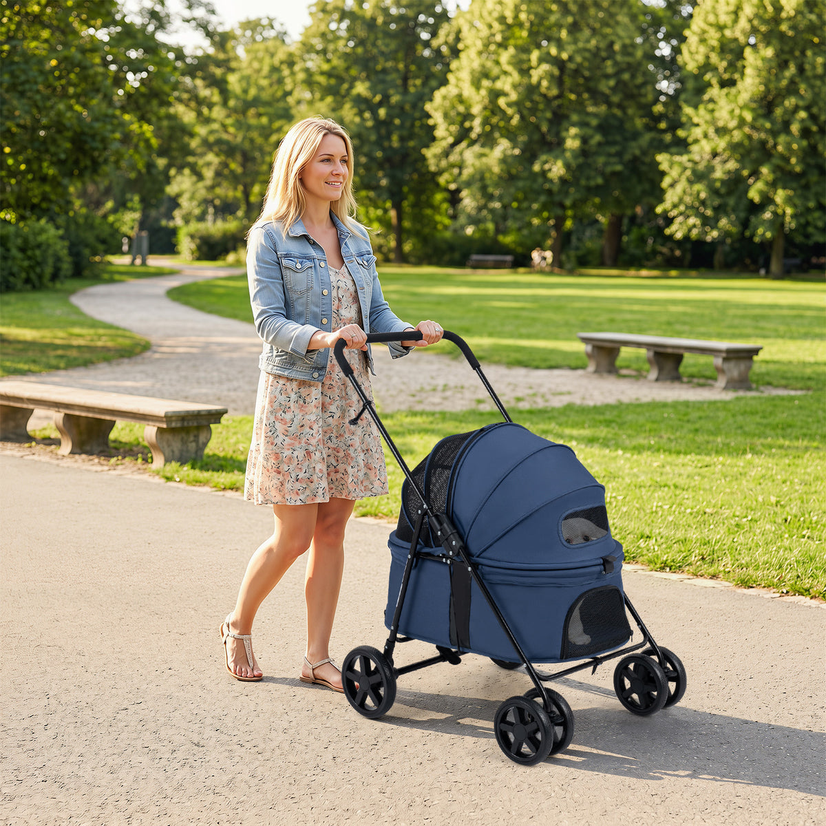 The dog stroller being pushed by a woman walking along a path in a green park