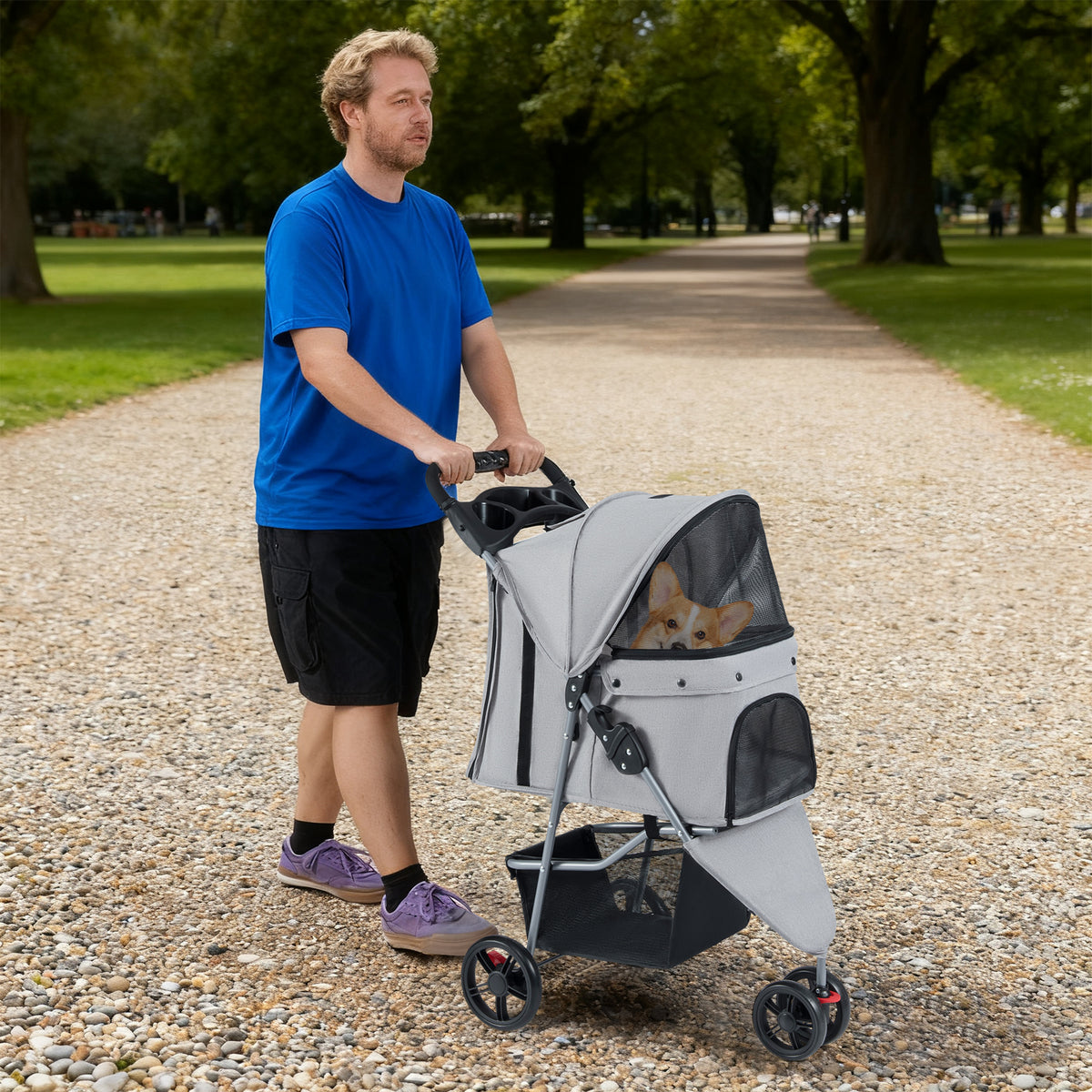 A man pushes the grey pet stroller with a dog in it along a path