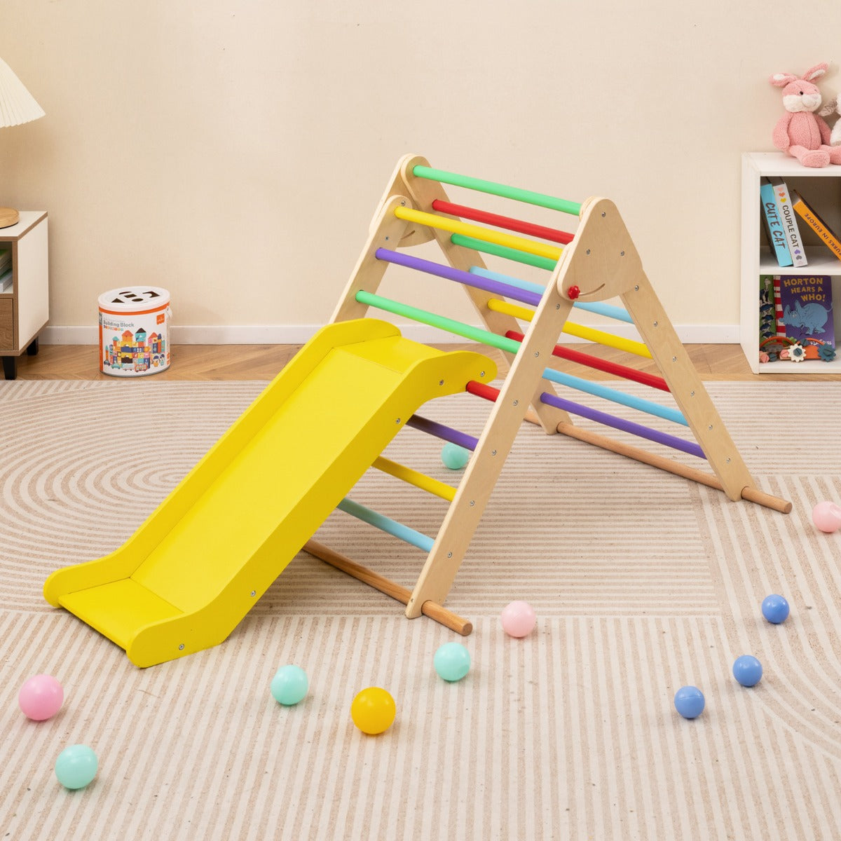 The climbing frame with a slide set up in a child's bedroom with scattered colourful balls