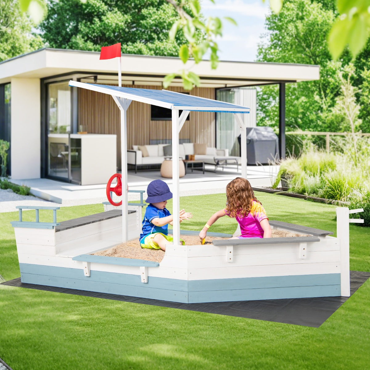 The pirate ship sandbox with canopy set up in a garden next to a modern house
