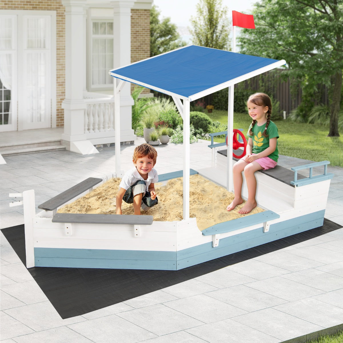 The pirate ship sandbox with canopy on a patio area with a house in the background