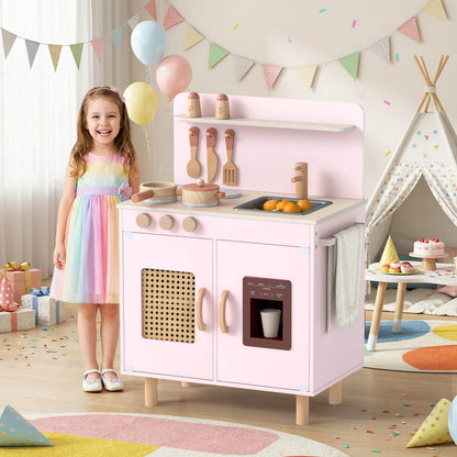 A young girl smiles next to the pink play kitchen set in a decorated room