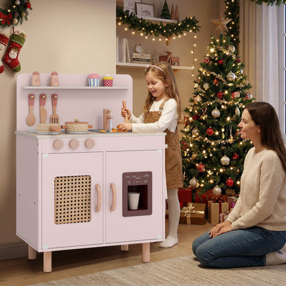 A mother and child play with the pink toy kitchen near a Christmas tree