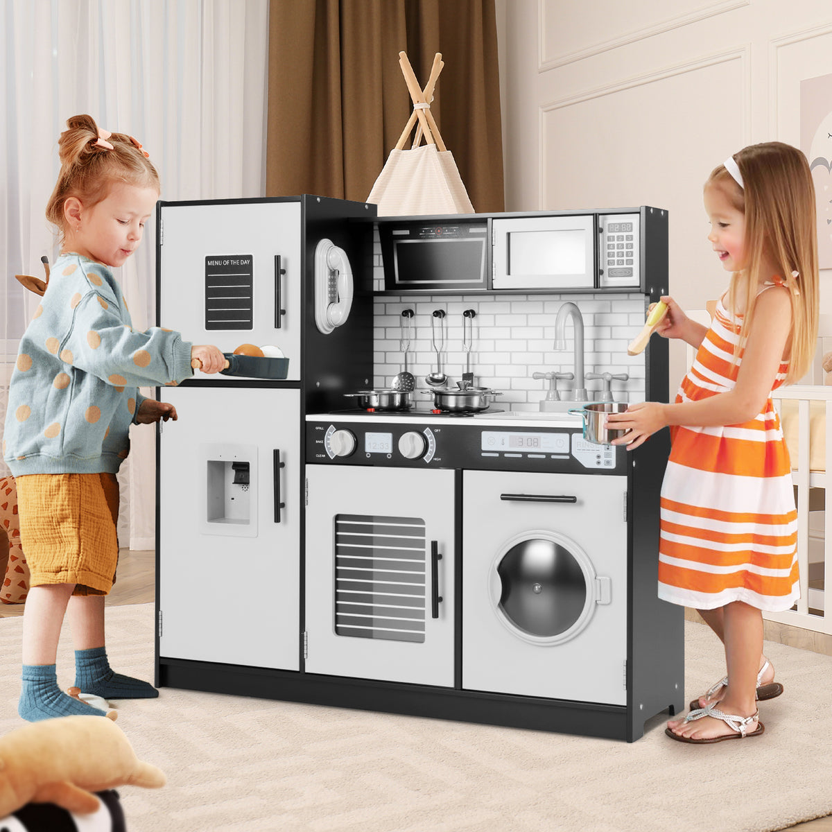 Two children playing with the black and white play kitchen set