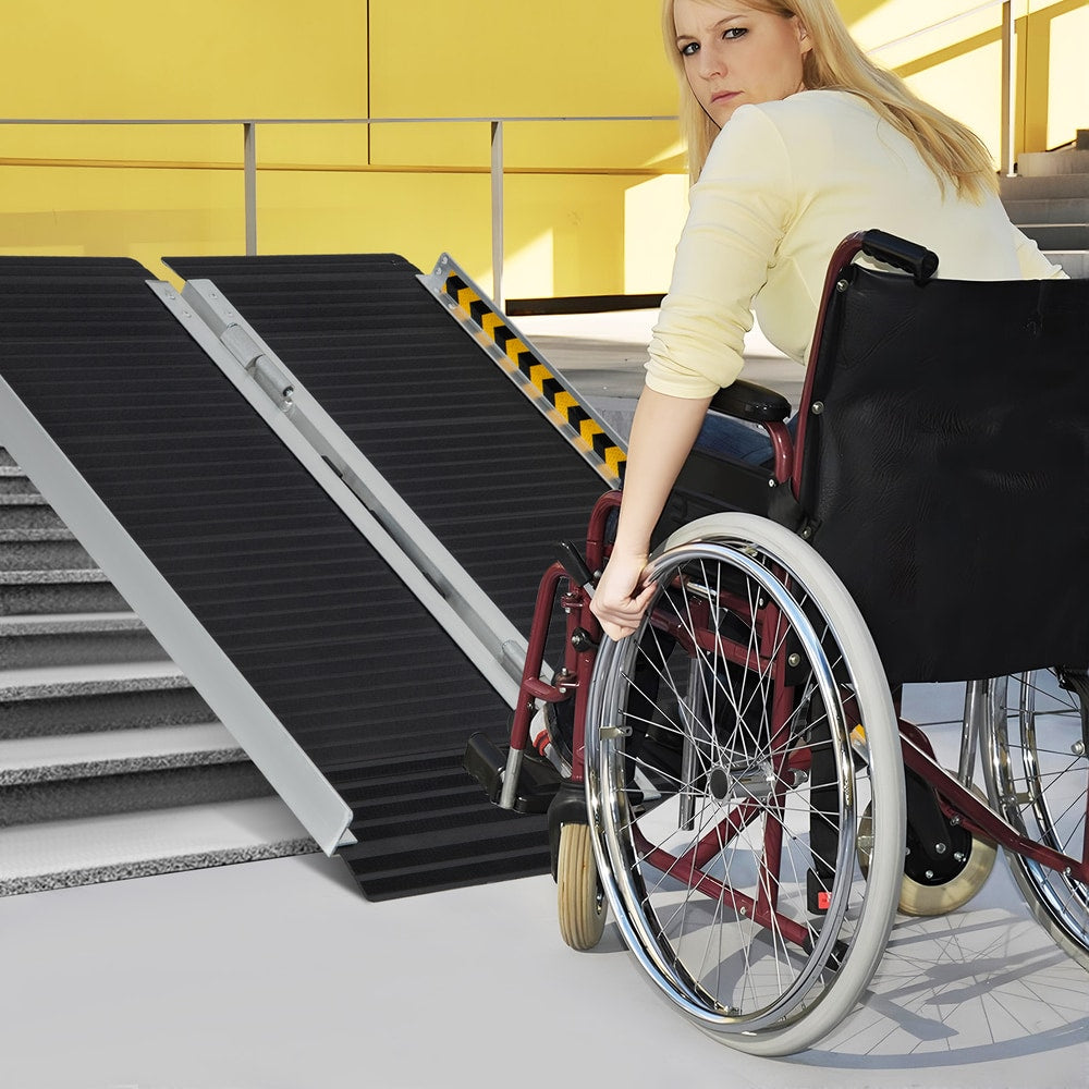 Woman in a wheelchair using the portable aluminum wheelchair ramp to ascend a set of steps
