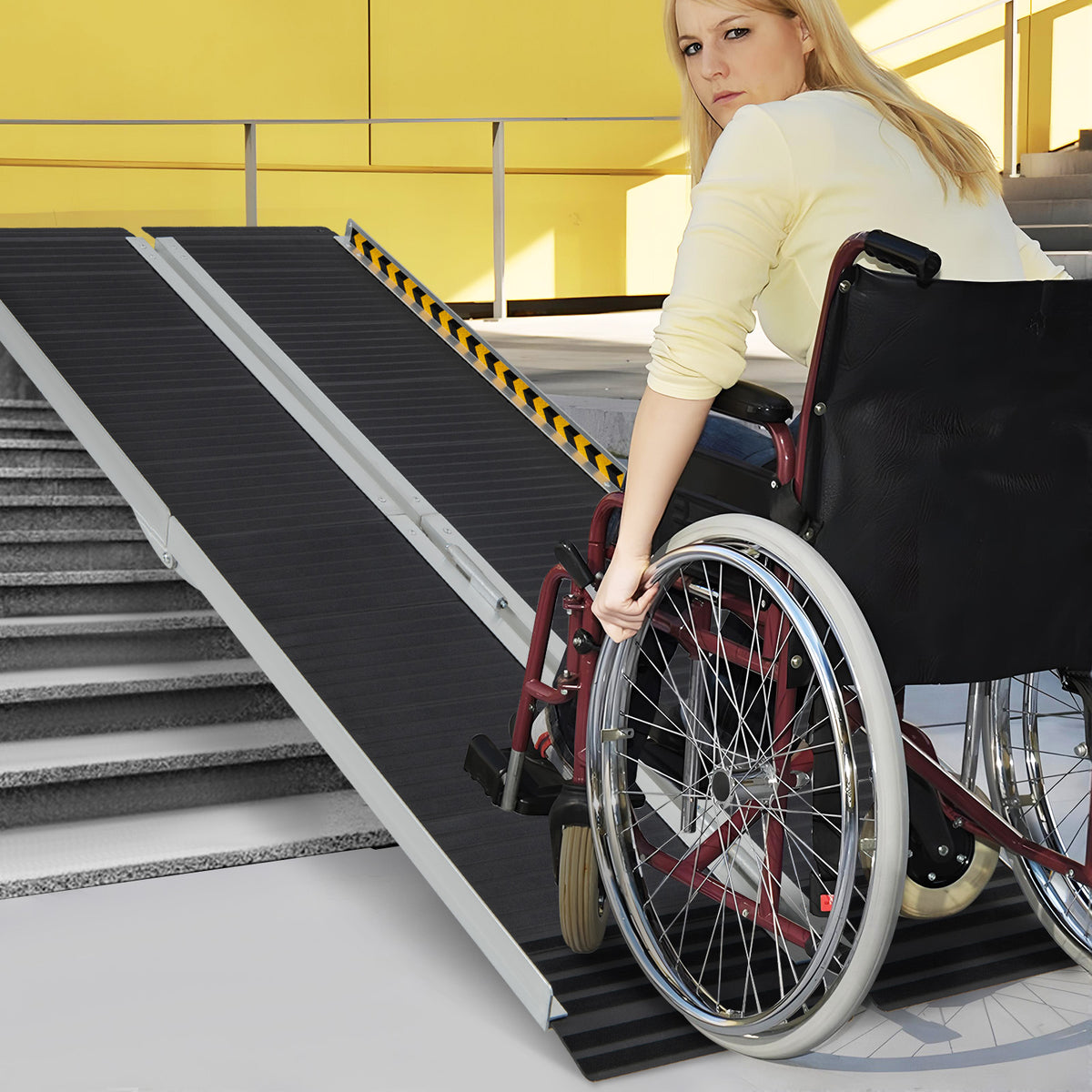 A woman in a wheelchair uses the portable aluminum wheelchair ramp to go up steps