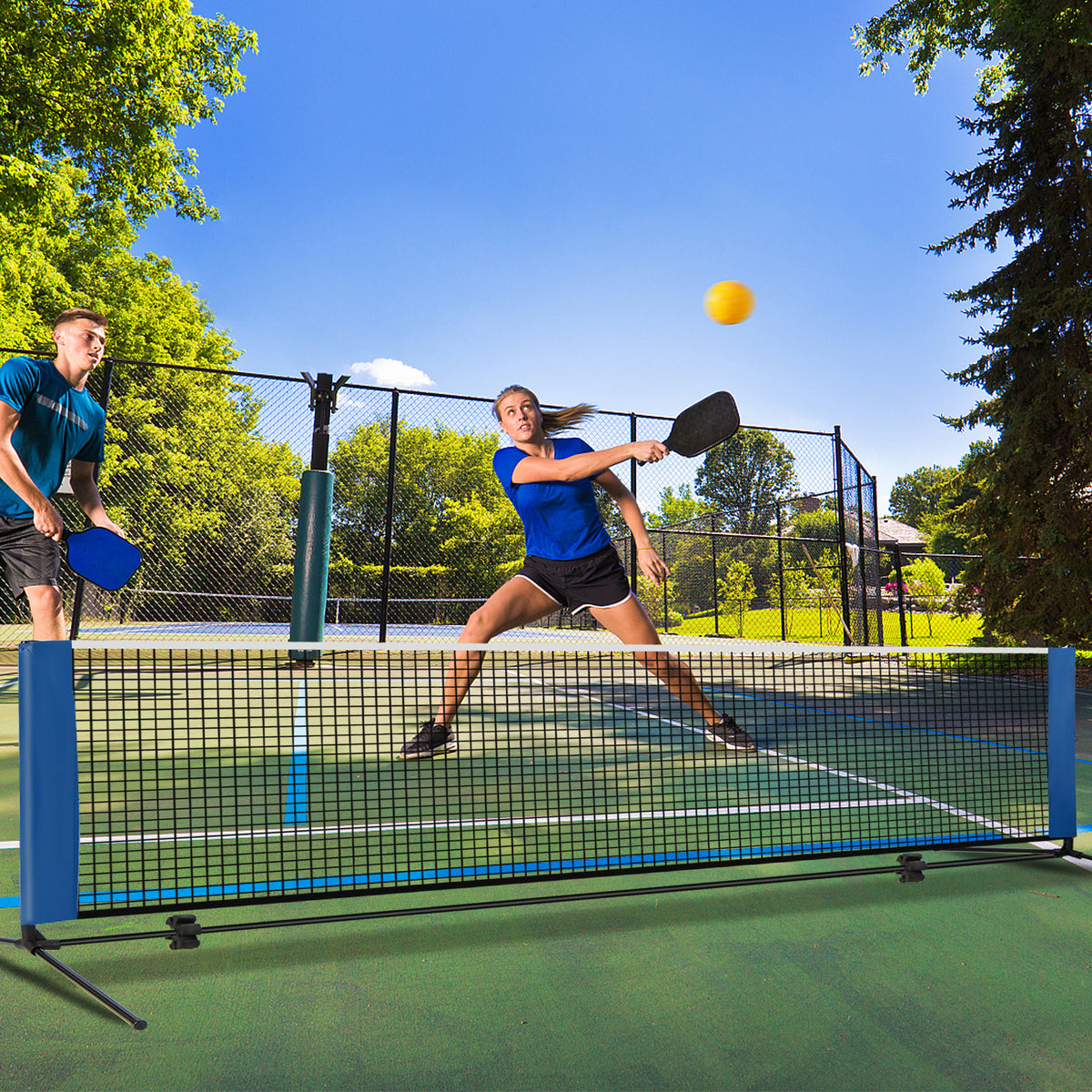 The blue badminton net being used for a game of pickleball with two players