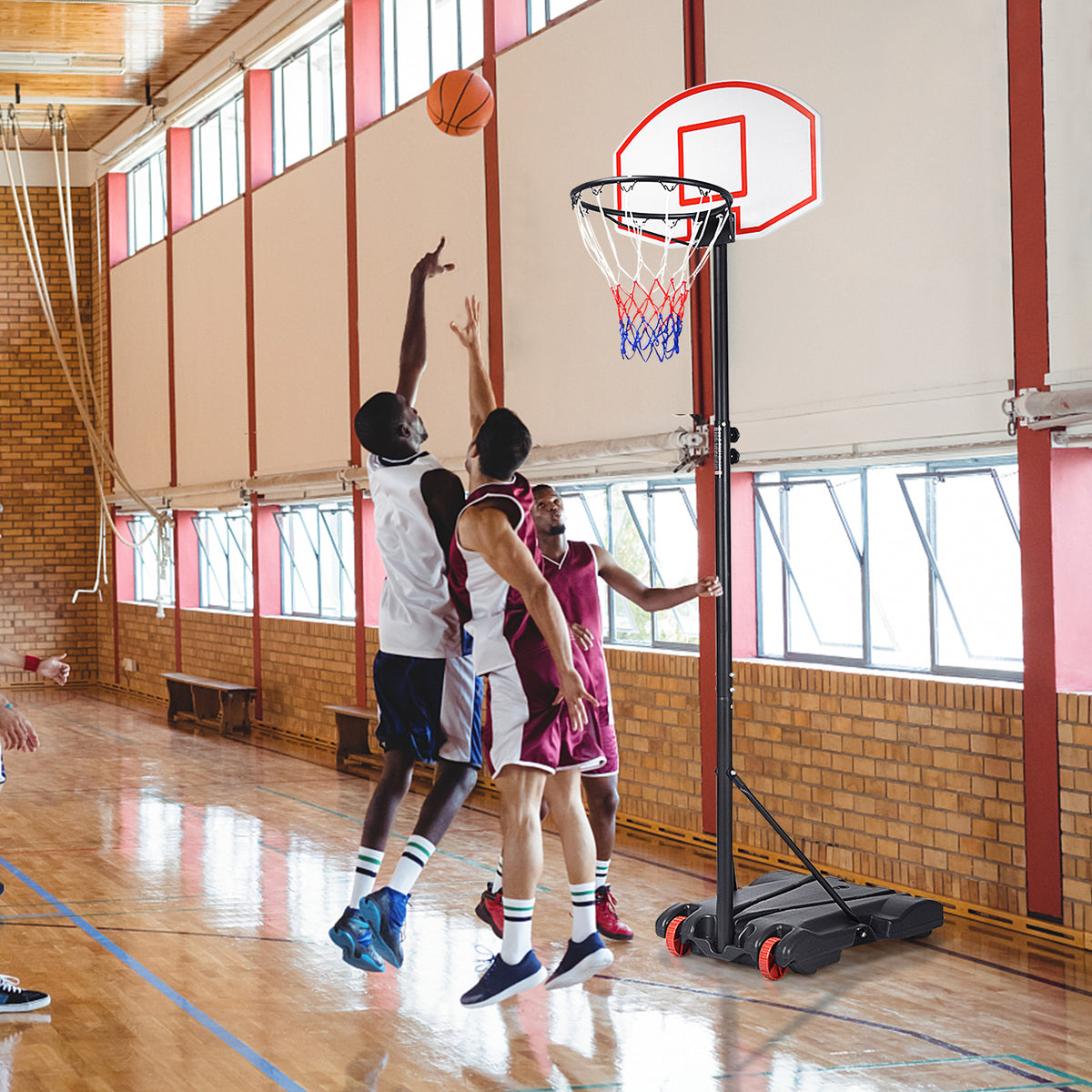 A portable basketball hoop in use during a game of basketball indoors