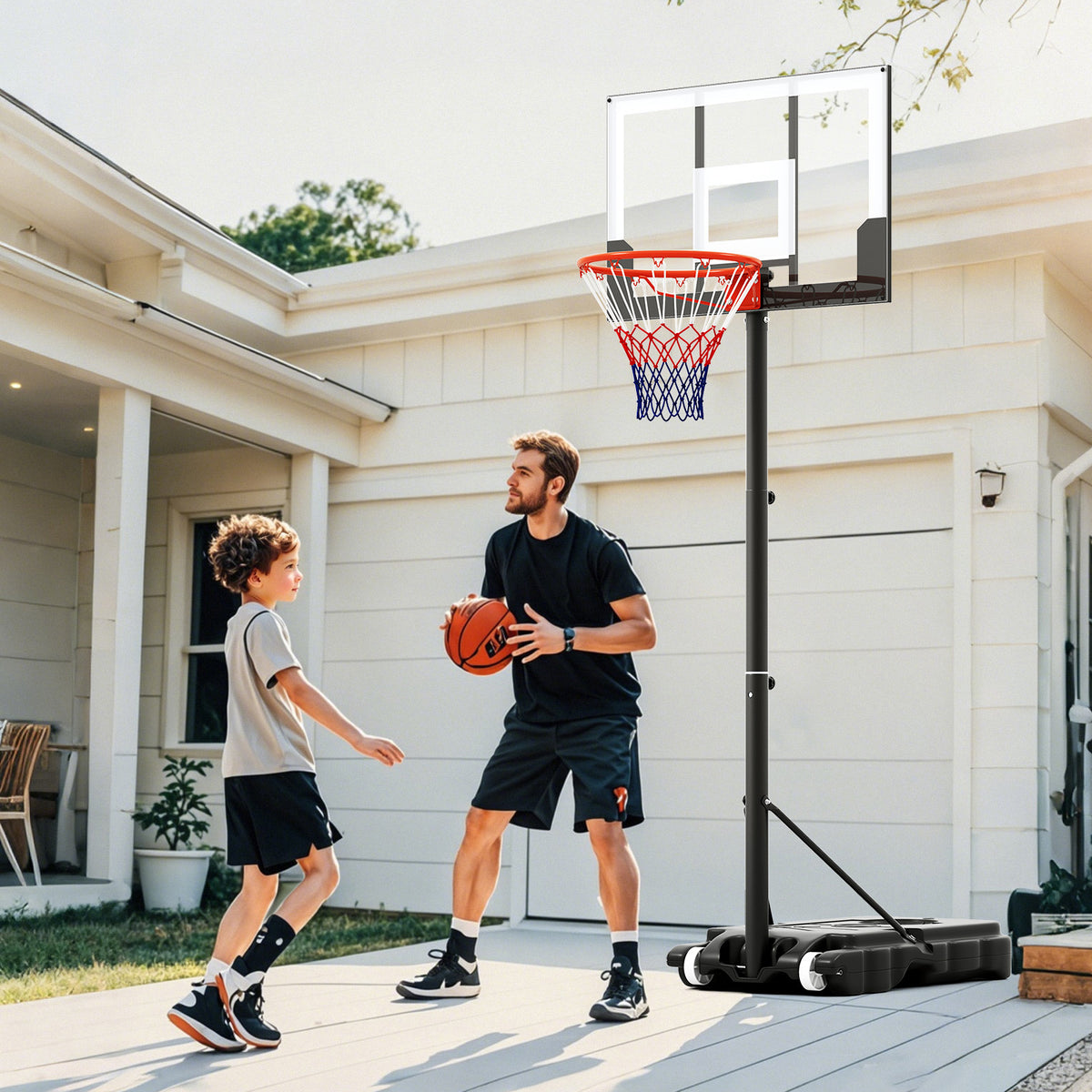 Father and son playing basketball with the portable hoop in a driveway