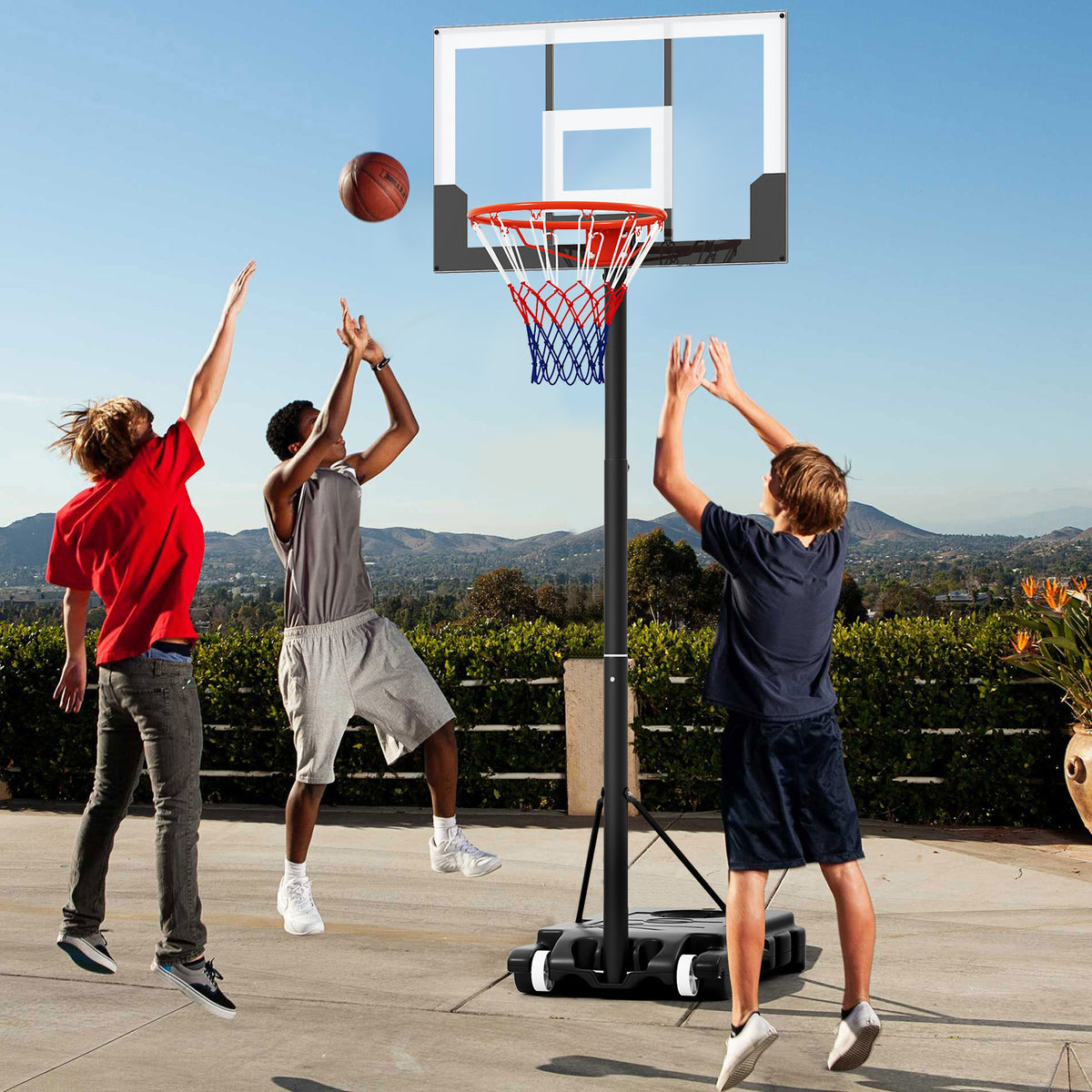 Three children playing basketball with the portable hoop on a patio
