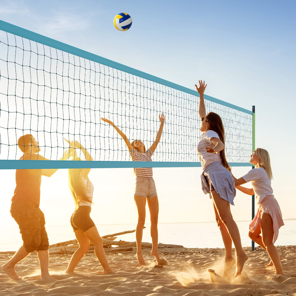 the volleyball net system set up on a sandy beach with a blue and yellow ball in the air