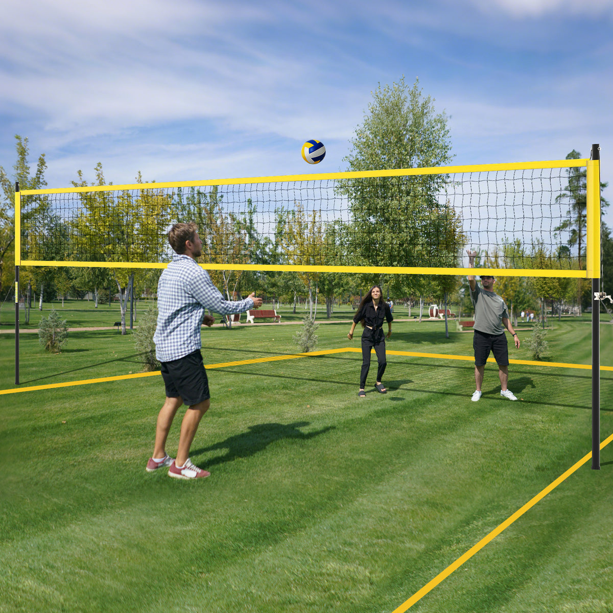People playing volleyball on a grassy park lawn with the yellow net system