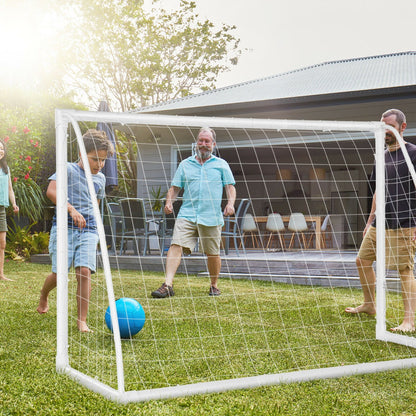 The soccer goal set up on a grassy lawn with a family playing a game together
