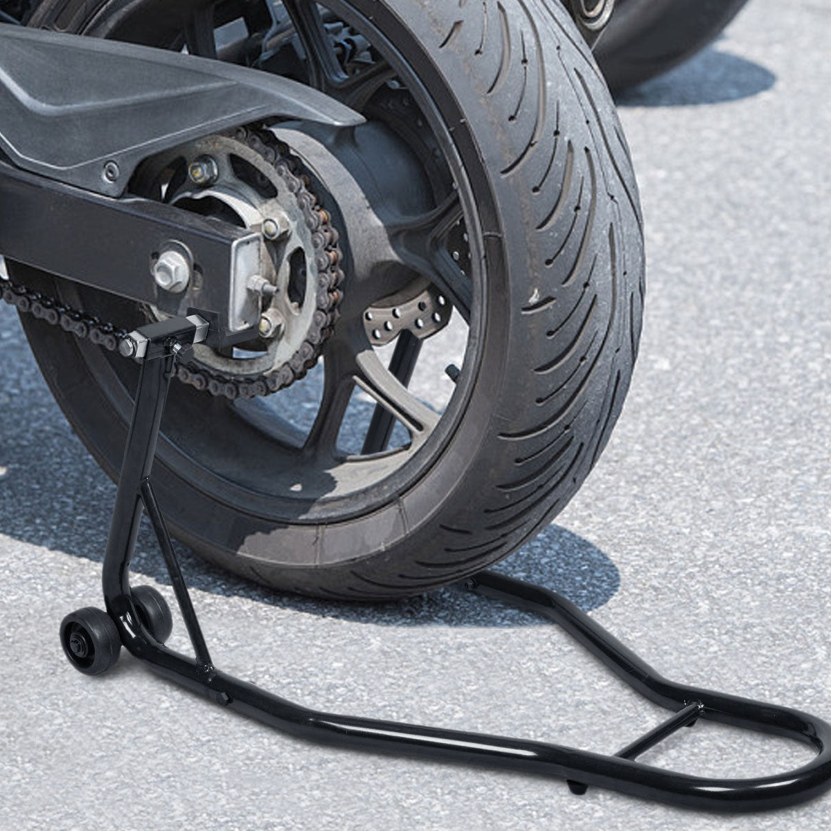 The rear wheel of a motorcycle is lifted by the black steel stand on tarmac