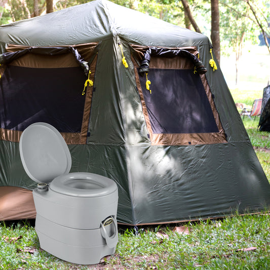 The camping toilet placed on the grass in front of a large green camping tent