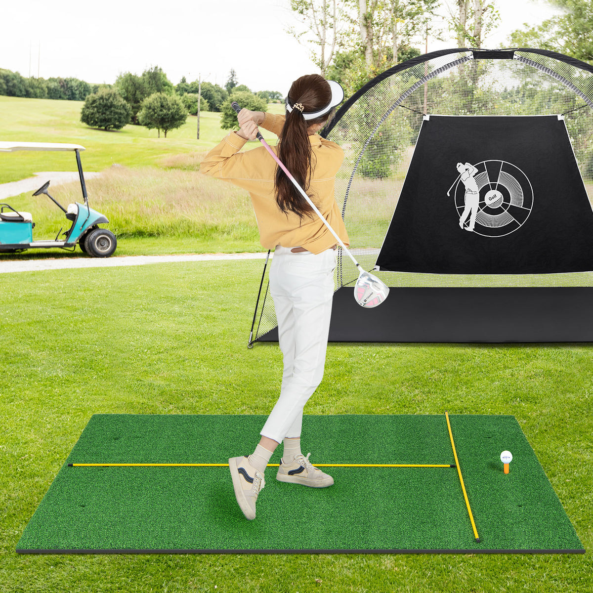 The golf practice mat placed on grass in front of a golf hitting net outdoors
