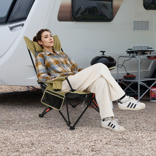 The green camping furniture is shown with a woman relaxing in it next to a caravan