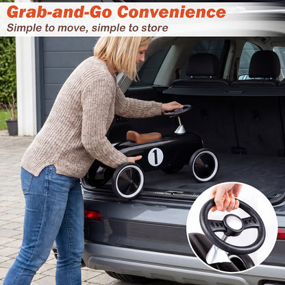 A woman places the black push and pedal ride on toy into the boot of a car