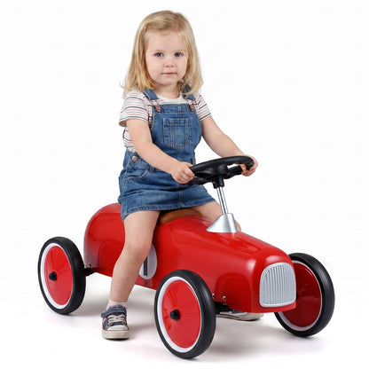 Ride on Push Car with a young girl sitting on the red toy vehicle against a plain white background