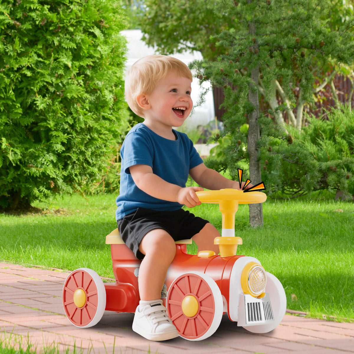 The ride on toy being used by a young boy on a paved path in a green garden