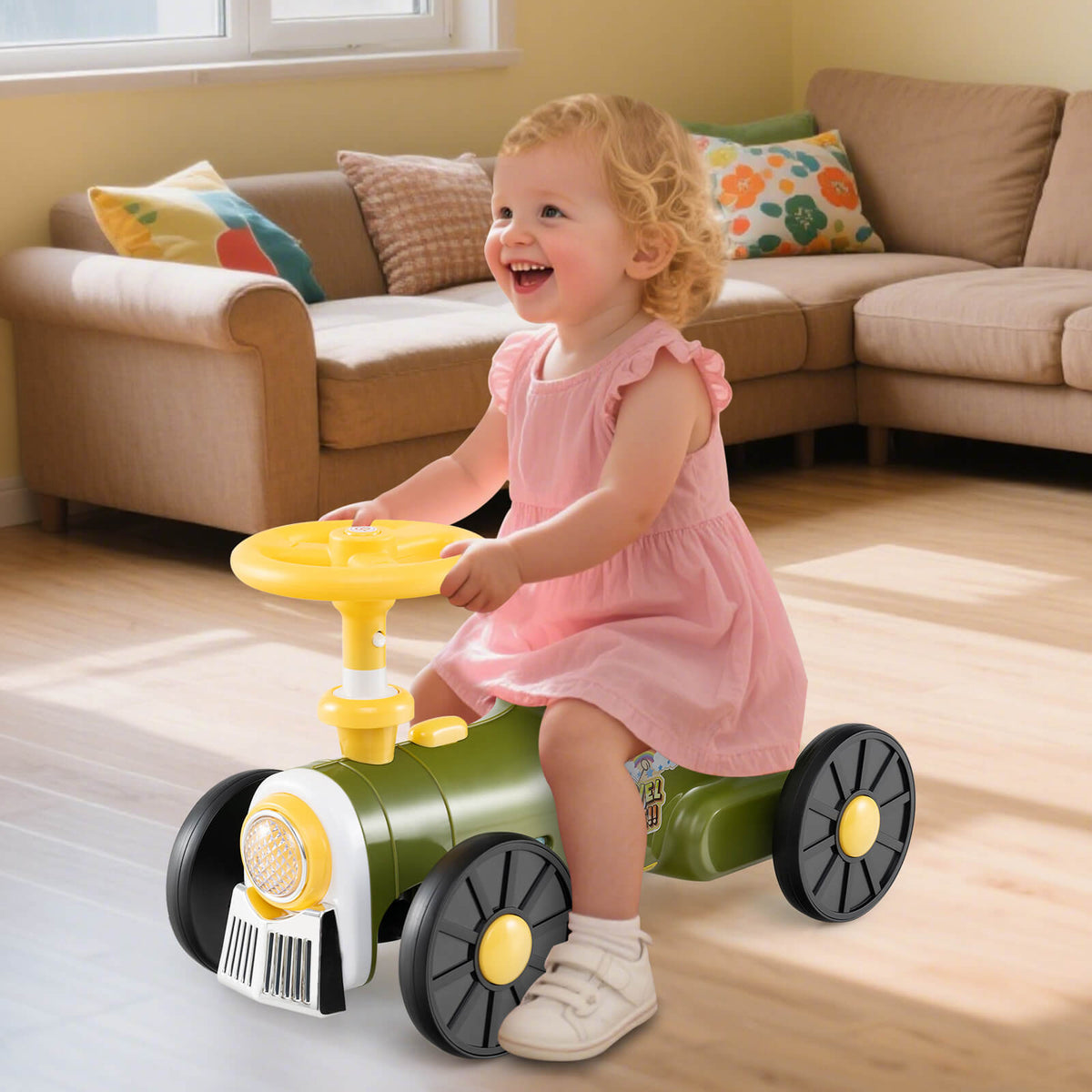 A happy toddler girl in a pink dress rides the green push car train indoors