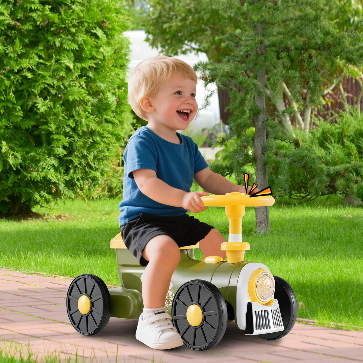 A smiling toddler boy in a blue t-shirt rides the green push car train outdoors