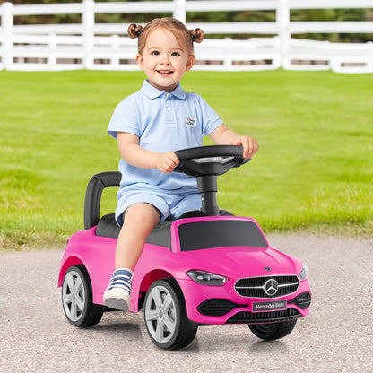 A happy toddler girl riding the pink push & pedal ride on toy outdoors