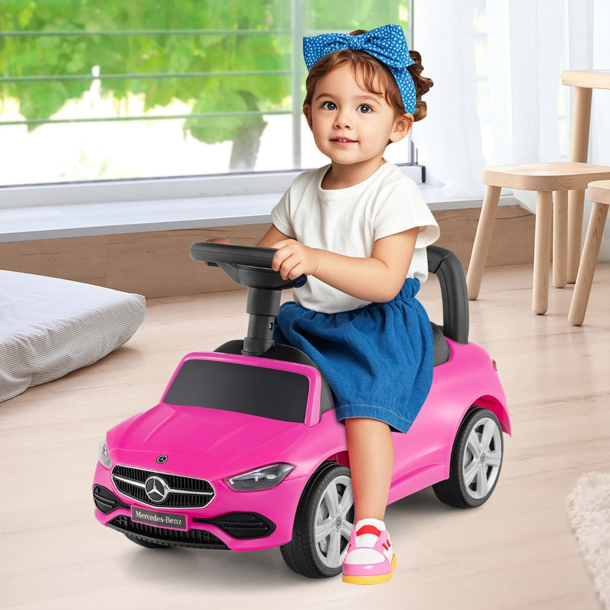 A young child sitting on the pink push & pedal ride on toy indoors