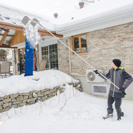 The roof rake snow removal tool being used to clear snow from a house roof