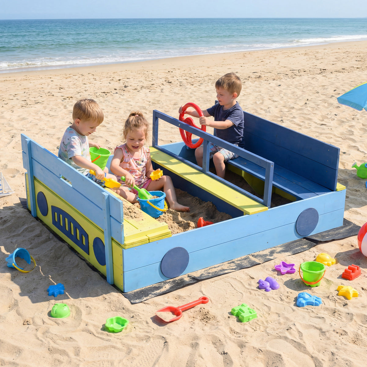The blue and yellow sandpit with a bench and steering wheel, on a beach with children