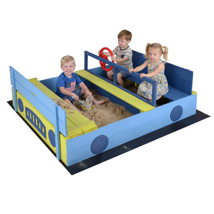 The wooden sandpit with a bench and steering wheel, with three children playing inside
