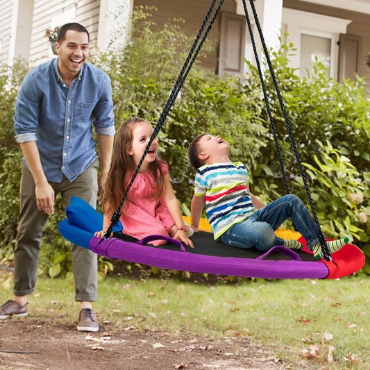 The swing in a garden with a man pushing two children sitting on the colourful seat