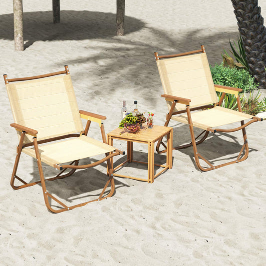Two beige camping chairs are set up on a sandy beach next to a small table