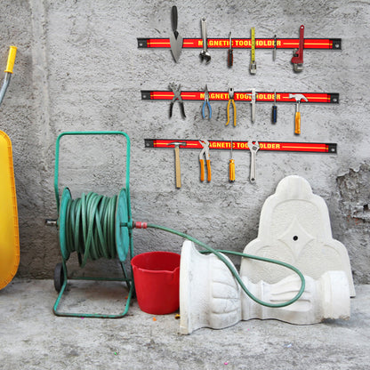 The magnetic storage bars fixed to a grey wall above a hose reel and garden items