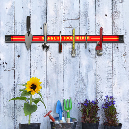 The garage storage strip holding tools on a rustic wooden wall above potted plants