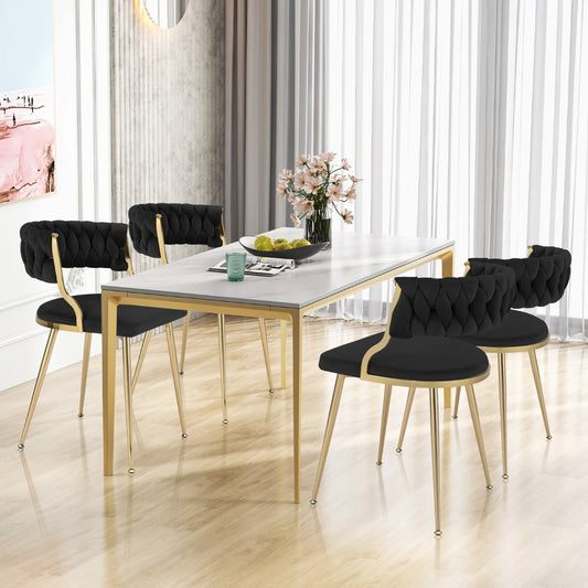 Four black velvet dining chairs around a white dining table in a modern room
