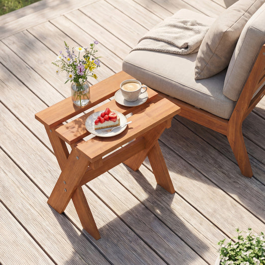 The small wooden table is shown next to a sofa on a decking area with a slice of cake and coffee on top