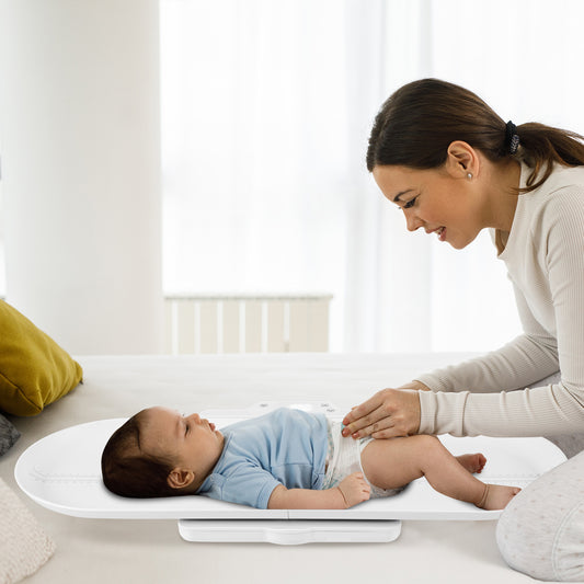 Smart Baby Scale with a baby lying on it while a woman adjusts its nappy