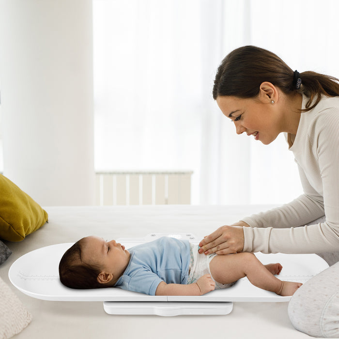 Smart Baby Scale with a baby lying on it while a woman adjusts its nappy