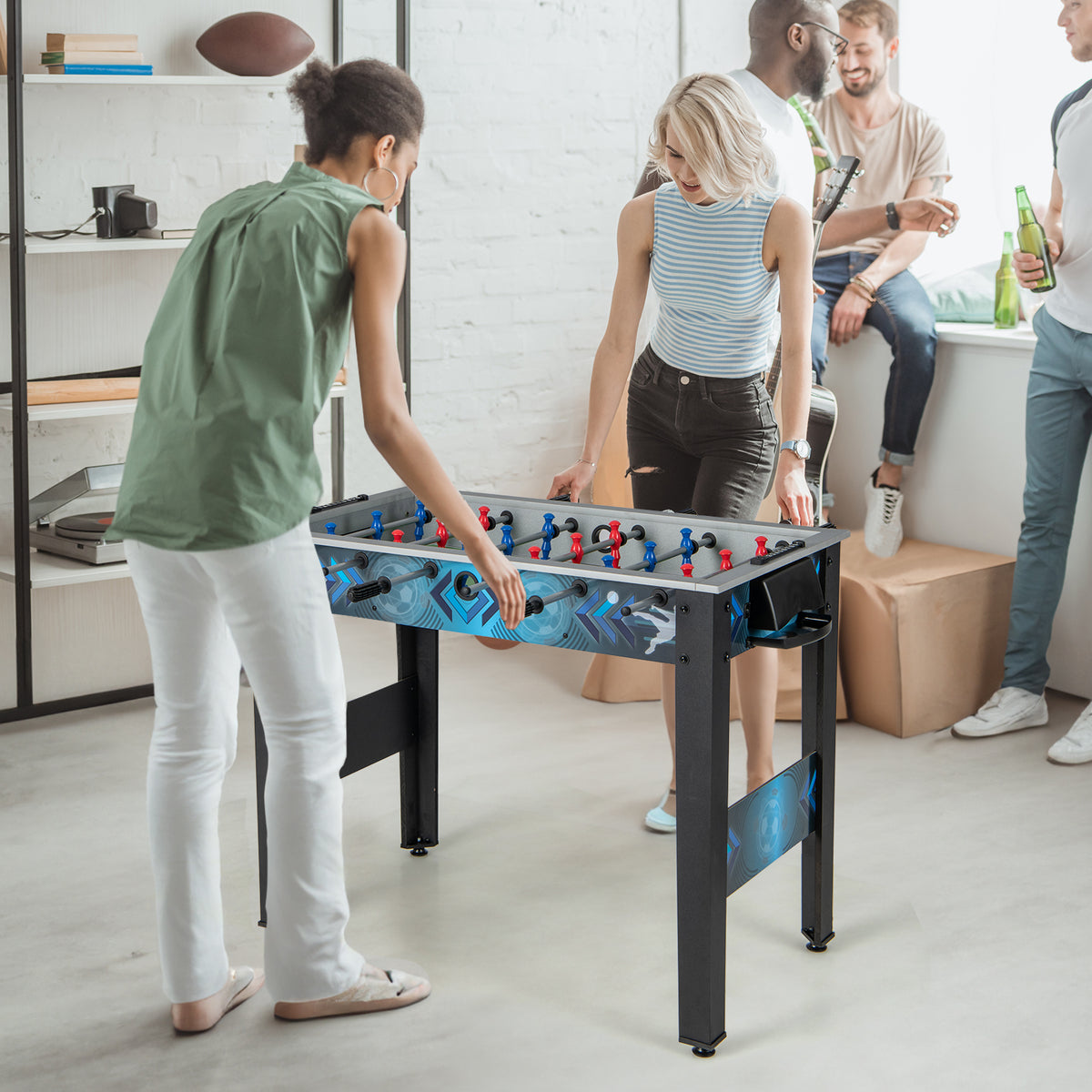 Group of adults and young people enjoying the tabletop football game at a party