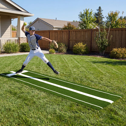 A young man pitches a softball on a green artificial turf training aid in a garden setting